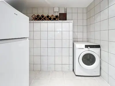 a white washing machine in a white tiled bathroom at Superbe maison F5 avec vue mer - Plage à 5 min - Climatisation - Wifi gratuit in Grosseto-Prugna