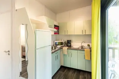 a kitchen with green cabinets and a white refrigerator at Camping Sole Di Sari in Sari Solenzara