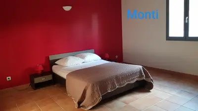 a bedroom with a bed with a red wall at Gite de 90m2 proche de la mer avec grande piscine MONTI in Canale-di-Verde