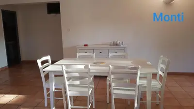 a white table with white chairs and a kitchen at Gite de 90m2 proche de la mer avec grande piscine MONTI in Canale-di-Verde