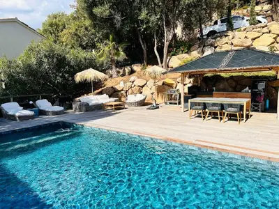 a swimming pool with a table and chairs next to a building at Villa Cala d Oro Vue mer Piscine et Crique privée in Sari Solenzara