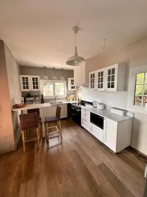 a kitchen with white cabinets and a wooden floor at Villa Cala d Oro Vue mer Piscine et Crique privée in Sari Solenzara