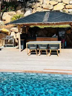 a picnic table and chairs next to a swimming pool at Villa Cala d Oro Vue mer Piscine et Crique privée in Sari Solenzara