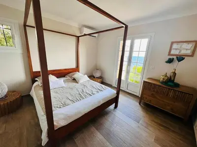 a bedroom with a four poster bed with a wooden frame at Villa Cala d Oro Vue mer Piscine et Crique privée in Sari Solenzara
