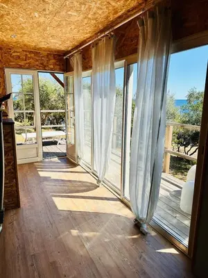 a room with sliding glass doors with a view of the ocean at Villa Cala d Oro Vue mer Piscine et Crique privée in Sari Solenzara