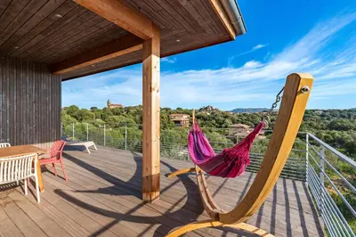 a hammock on the deck of a house at Villa Ondella - Villa entre plages et sentiers in Pianottoli-Caldarello