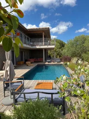 a swimming pool with two chairs and a house at Villa Ondella - Villa entre plages et sentiers in Pianottoli-Caldarello