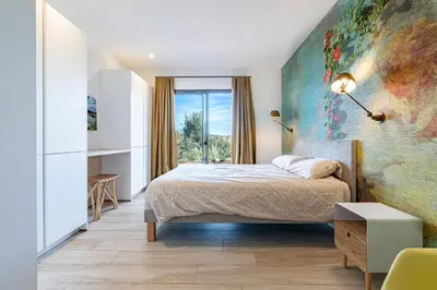 a bedroom with a bed and a large painting on the wall at Villa Ondella - Villa entre plages et sentiers in Pianottoli-Caldarello