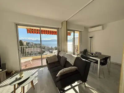 a living room with a couch and a large window at Studio vue mer le Neptune sanguinaires Ajaccio in Ajaccio