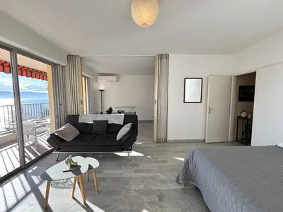 a bedroom with a bed and a couch and a balcony at Studio vue mer le Neptune sanguinaires Ajaccio in Ajaccio