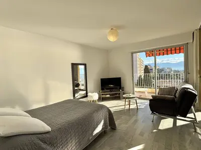 a bedroom with a bed and a chair and a large window at Studio vue mer le Neptune sanguinaires Ajaccio in Ajaccio