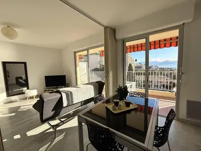 a bedroom with a bed and a living room with a balcony at Studio vue mer le Neptune sanguinaires Ajaccio in Ajaccio
