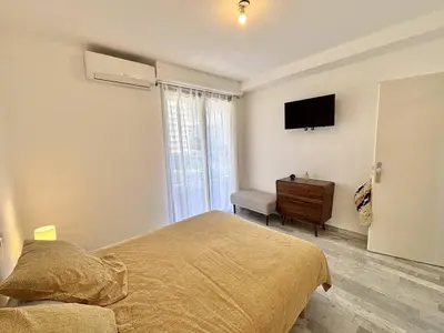 a bedroom with a bed and a television on the wall at F2 Vue mer le Neptune sanguinaires Ajaccio in Ajaccio