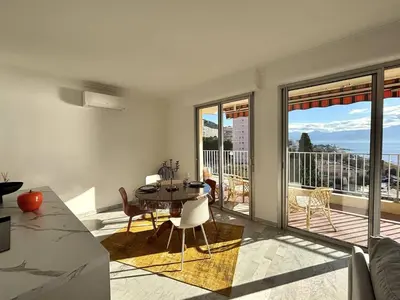 a living room with a table and chairs and a balcony at F2 Vue mer le Neptune sanguinaires Ajaccio in Ajaccio