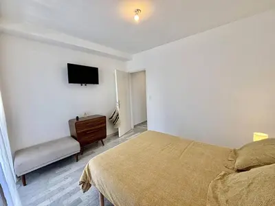 a bedroom with a bed and a tv on the wall at F2 Vue mer le Neptune sanguinaires Ajaccio in Ajaccio