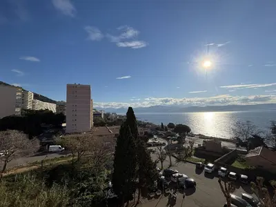 a view of a city with the sun shining over the water at F2 Vue mer le Neptune sanguinaires Ajaccio in Ajaccio