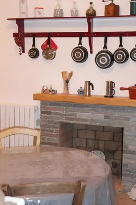 a kitchen with a brick fireplace with pots and pans at Appartement Vezzani Centre Corse in Vezzani