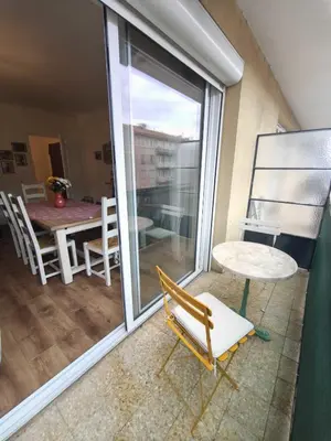 a room with a balcony with a table and a chair at Charming T3 with balconies in Ajaccio in Ajaccio