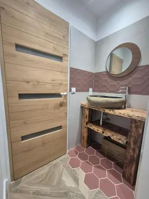 a bathroom with a wooden door and a sink at CasaKia in Pietralba