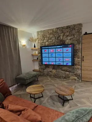 a living room with a tv on a stone wall at CasaKia in Pietralba