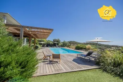 a pool with chairs and an umbrella next to a house at Villa d’exception 4 chambres, piscine, vue mer in Porto-Vecchio
