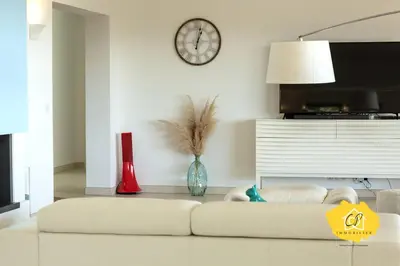 a living room with a white couch and a clock on the wall at Villa d’exception 4 chambres, piscine, vue mer in Porto-Vecchio