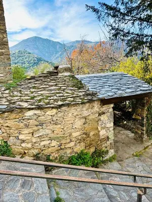 a stone building with a slate roof with mountains in the background at Charming village house in Cambia