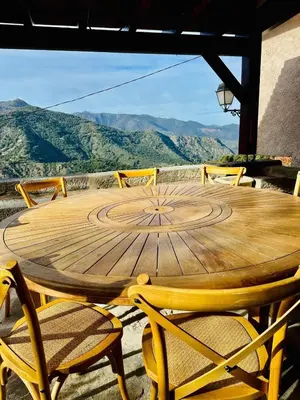 a wooden table and chairs with a view of mountains at Charming village house in Cambia