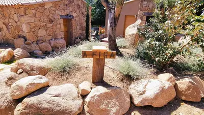 a wooden cross in a garden with rocks at Domaine de Gialla Bergerie Figa, 2 pers, piscine chauffée, 10 mn plage in Arraggio