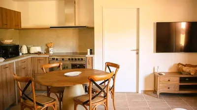 a kitchen with a wooden table with chairs and a stove at Domaine de Gialla Bergerie Quercia, 2 pers, piscine chauffée, 10 mn plage in Arraggio