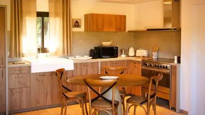 a kitchen with a wooden table and chairs in it at Domaine de Gialla Bergerie Quercia, 4 pers, piscine chauffée, 10 mn plage in Arraggio