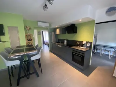 a kitchen with green walls and a table and chairs at villa jérémy in Bonifacio