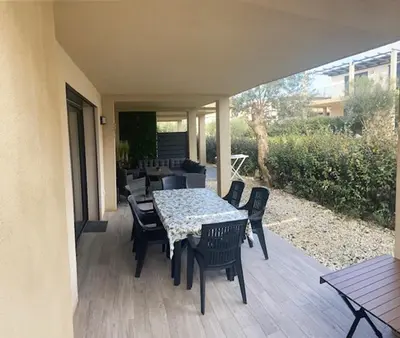 a patio with a table and chairs on a deck at villa jérémy in Bonifacio