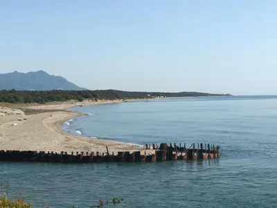 a pier in the water next to a beach at casa di santa in Aléria