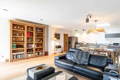 a living room with a black leather couch and a kitchen at casa di santa in Aléria