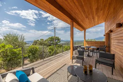 a wooden deck with tables and chairs on a balcony at Chalet U Picculu Di Arasu in Sainte-Lucie de Porto-Vecchio