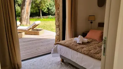 a bedroom with a bed and a porch with a chair at Domaine de Gialla Bergerie I Pini, 8 pers, piscine chauffée, 10 mn plage in Arraggio