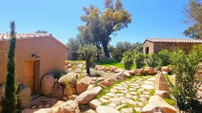 a garden with rocks and a building and trees at Domaine de Gialla Bergerie Prugna, 8 pers, piscine chauffée, 10 mn plage in Arraggio