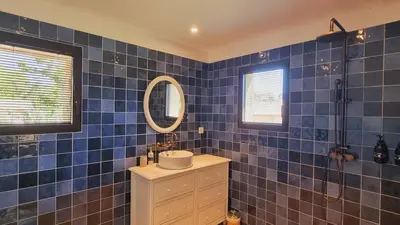 a blue tiled bathroom with a sink and a mirror at Domaine de Gialla Bergerie Prugna, 8 pers, piscine chauffée, 10 mn plage in Arraggio