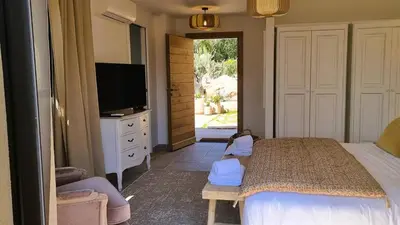 a bedroom with a bed and a tv and a door at Domaine de Gialla Bergerie Prugna, 8 pers, piscine chauffée, 10 mn plage in Arraggio