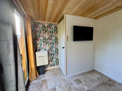 a room with a flat screen tv on a wall at Maisonette les pieds dans l'eau in Pietrosella