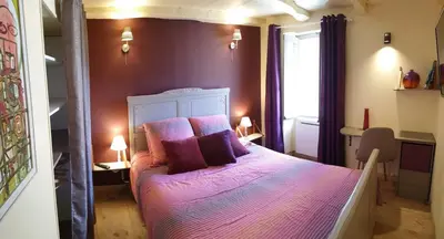 a bedroom with a bed with purple sheets and pillows at 10 min de Cortè, 5 couchages, in Venaco