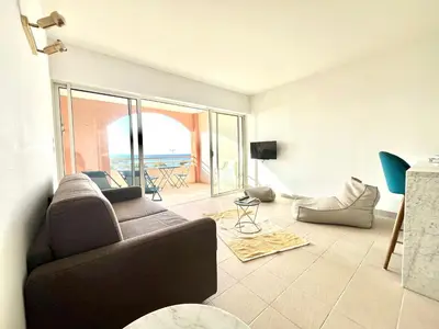 a living room with a couch and a view of the ocean at Superbe Studio pieds dans l'eau - Parking gratuit - Terrasse - Emplacement idéal dans résidence de standing in Ajaccio