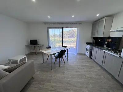 a living room with a table and a kitchen at U TERZU - Appart neuf spacieux in Aléria