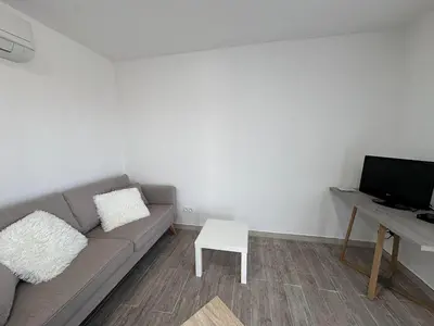 a living room with a couch and a table and a television at U TERZU - Appart neuf spacieux in Aléria