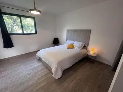 a bedroom with a bed and a lamp on a wooden floor at U TERZU - Appart neuf spacieux in Aléria
