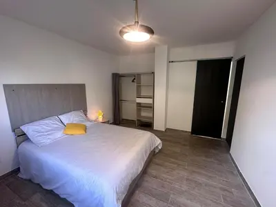 a bedroom with a white bed with a yellow pillow at U TERZU - Appart neuf spacieux in Aléria