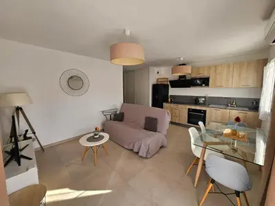 a living room with a couch and a glass table at Appartement moderne à Lucciana avec terrasse ensoleillée. in Lucciana