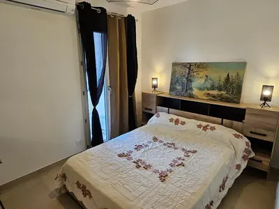 a bedroom with a bed and a painting on the wall at Appartement moderne à Lucciana avec terrasse ensoleillée. in Lucciana