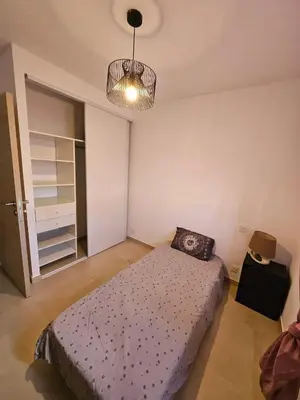 a bedroom with a bed and a chandelier at Appartement moderne à Lucciana avec terrasse ensoleillée. in Lucciana